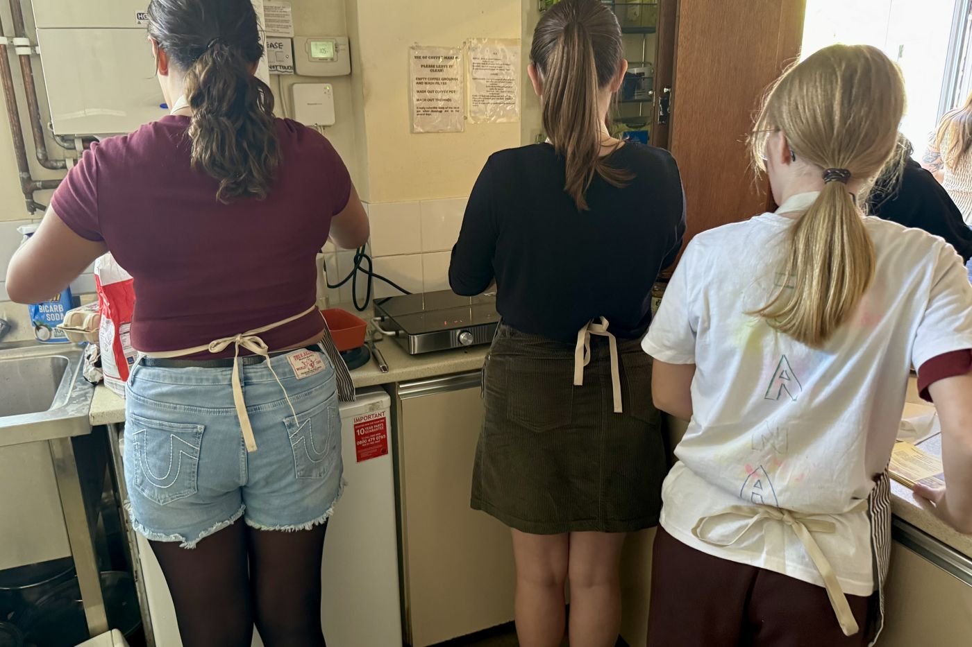 Young people in aprons cooking together in the kitchen